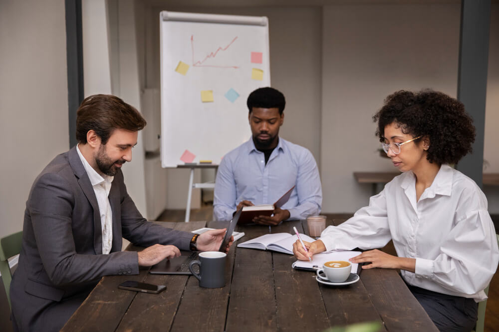 reunião com 3 pessoas na mesa em ambiente corporativo