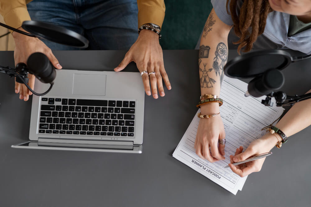 Mãos no teclado de notebook com ícones digitais representando finanças e comunicação empresarial