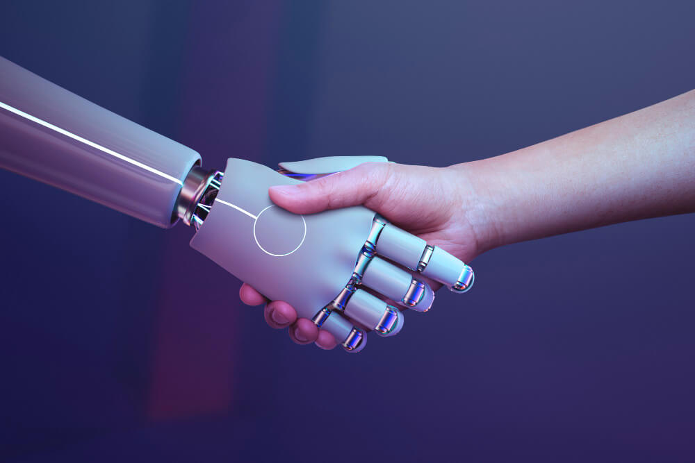 Mão humana apertando a mão de um robô em sinal de colaboração com inteligência artificial.